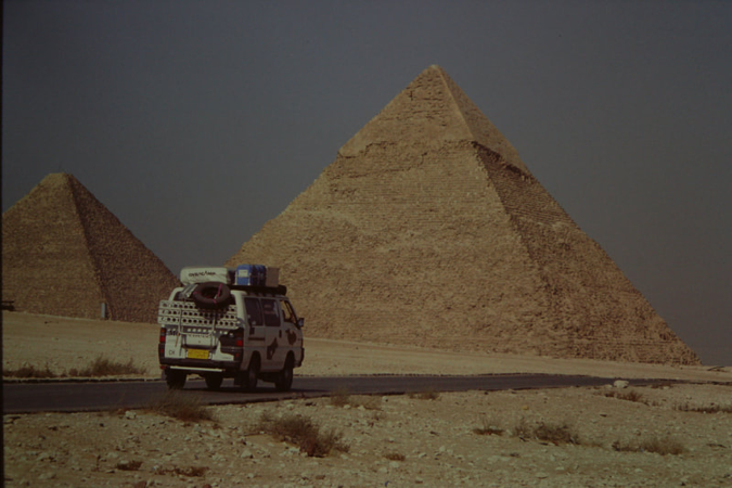 Mitsubishi-Bus von hinten auf der Pistenstrasse vor den grossen Pyramiden von Giza